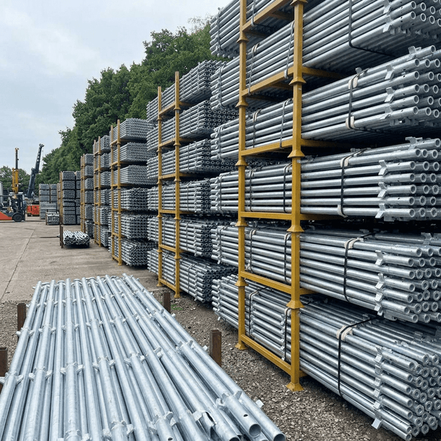 Galvanized kwikstage standards stacked outdoors in a supply yard